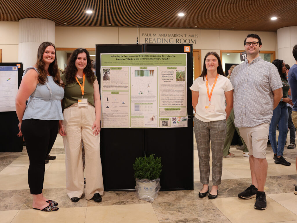 Standing from left to right; BiGG mentor Allyson Dekovich, scholar Olivia Degreenia, scholar Elisabeth Leung, and BiGG mentor Zane Smith standing near a research poster